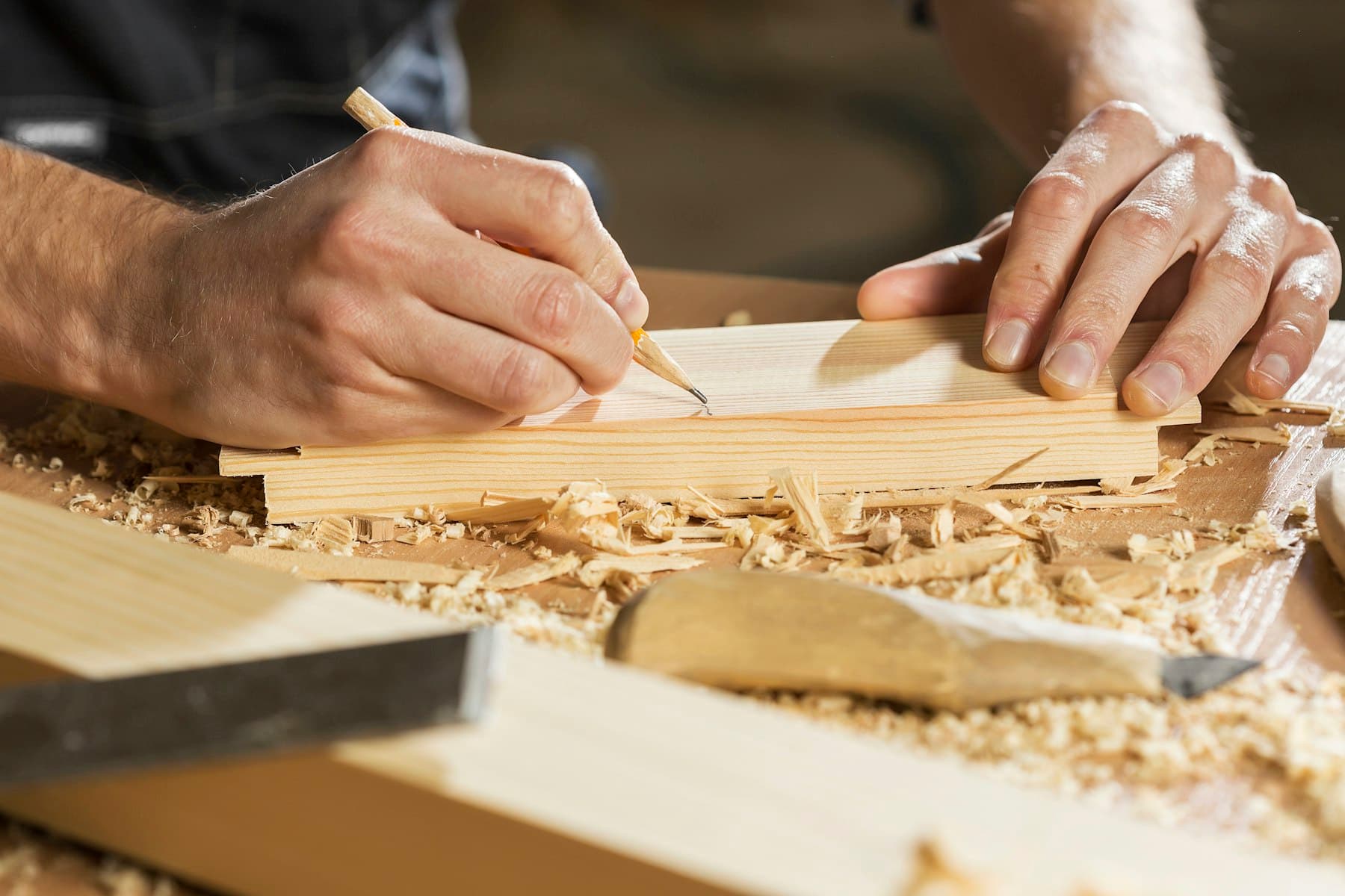 Carpenter measuring and marking a board in a workshop