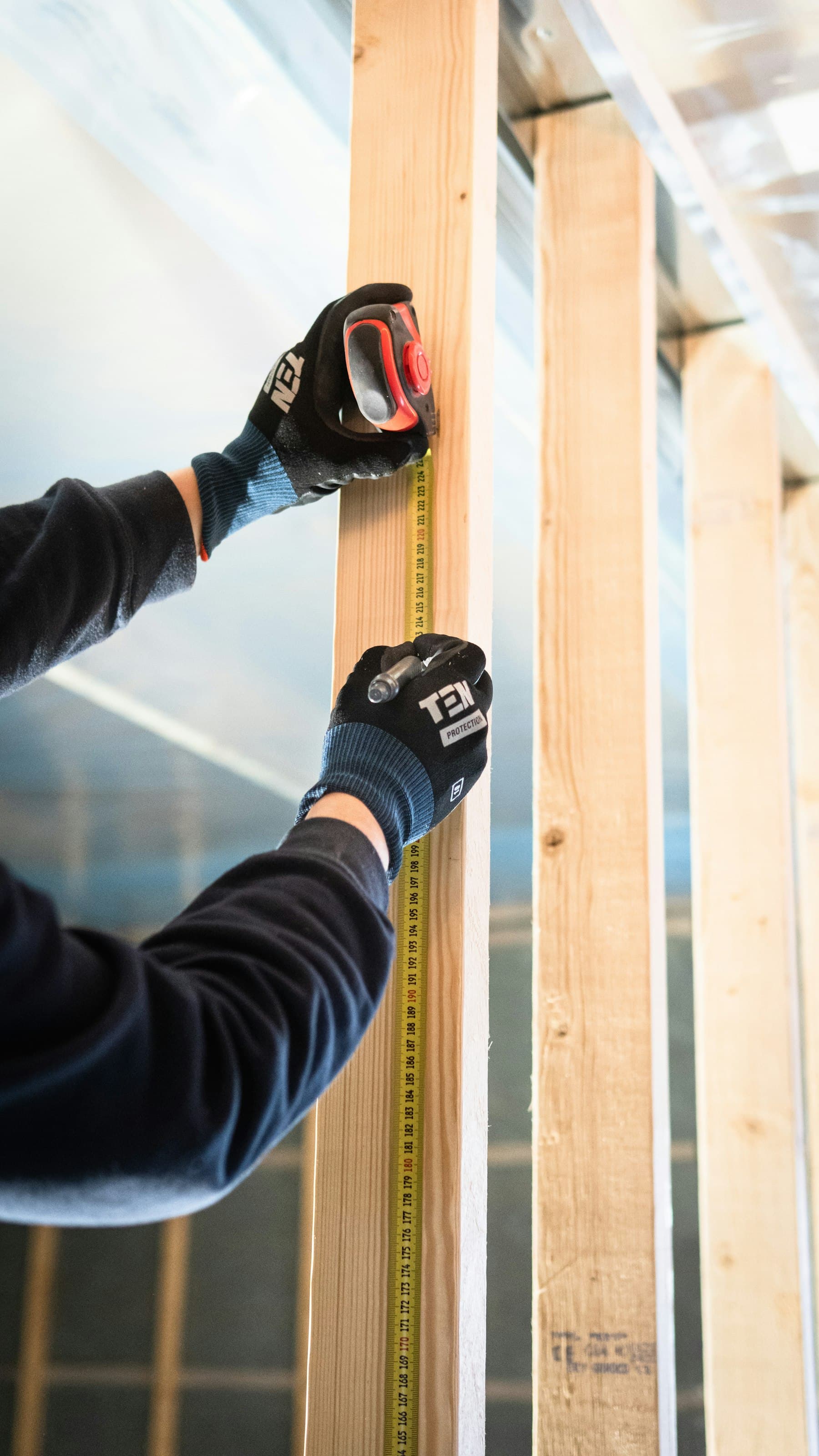 Handyman measuring and marking wall framing for a repair